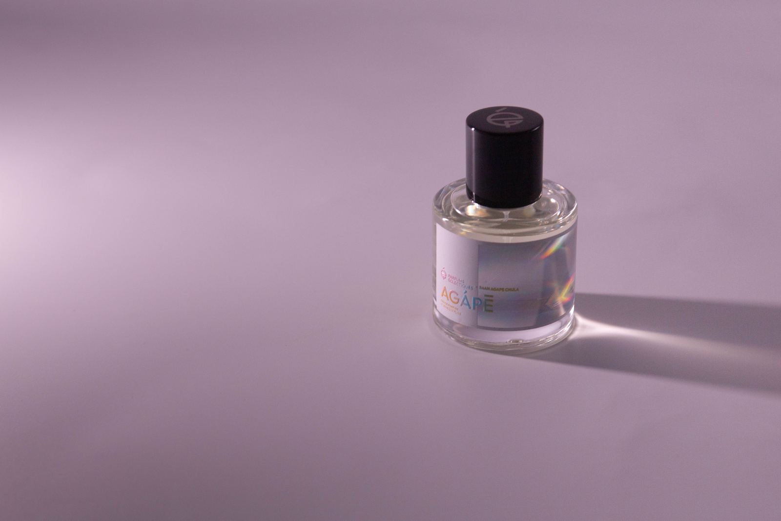 Agápē eau de parfum with a holographic label on a lilac-grey backdrop