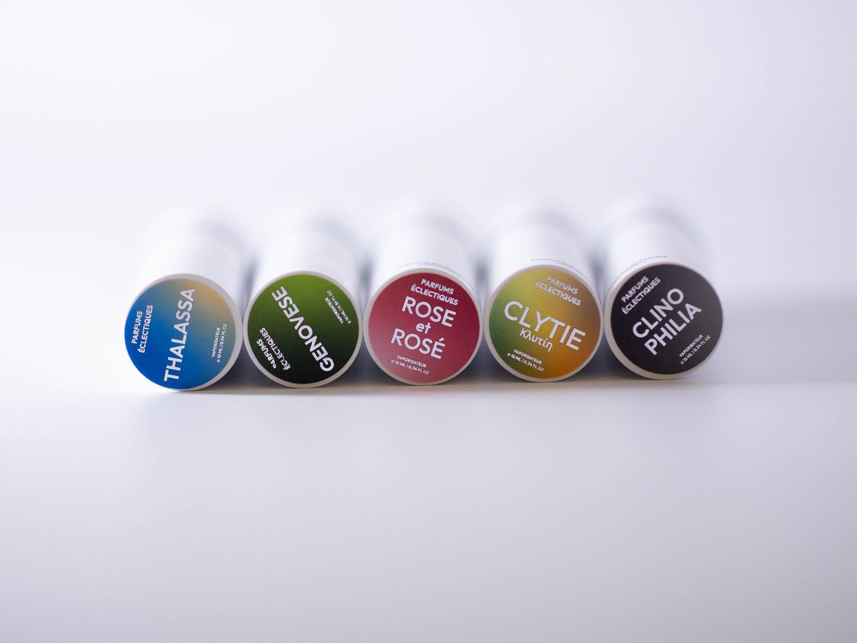 Five 10 ml travel sprays lying side by side, each cap labelled in its fragrance colour